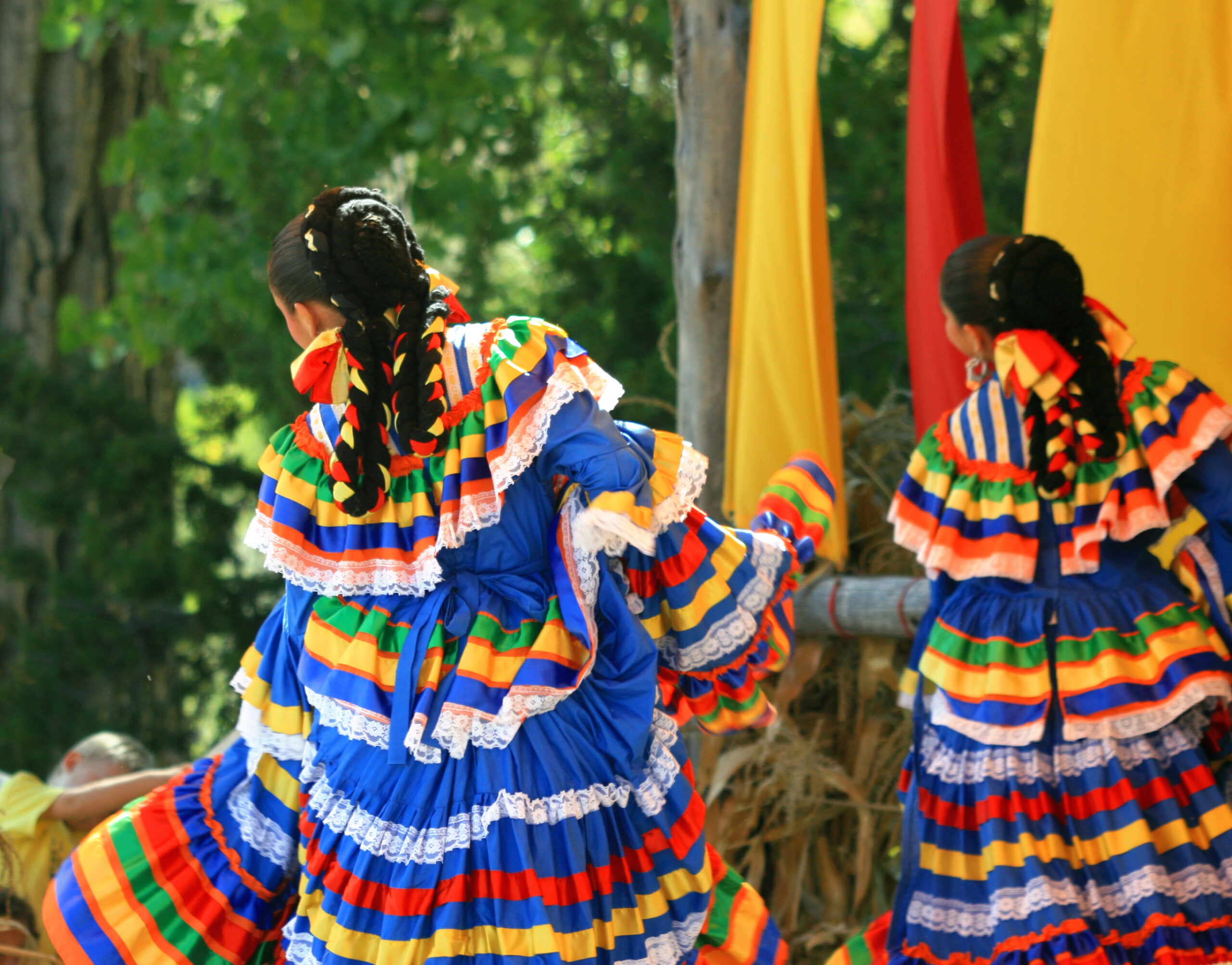 Folklorico dancers in colorful dresses adorned in ribbons and lace trim